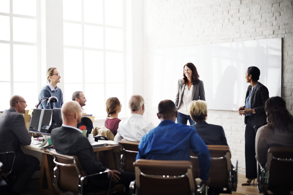 Professionals attend an event marketing session with speakers at the front, creating real-time connections and energy.